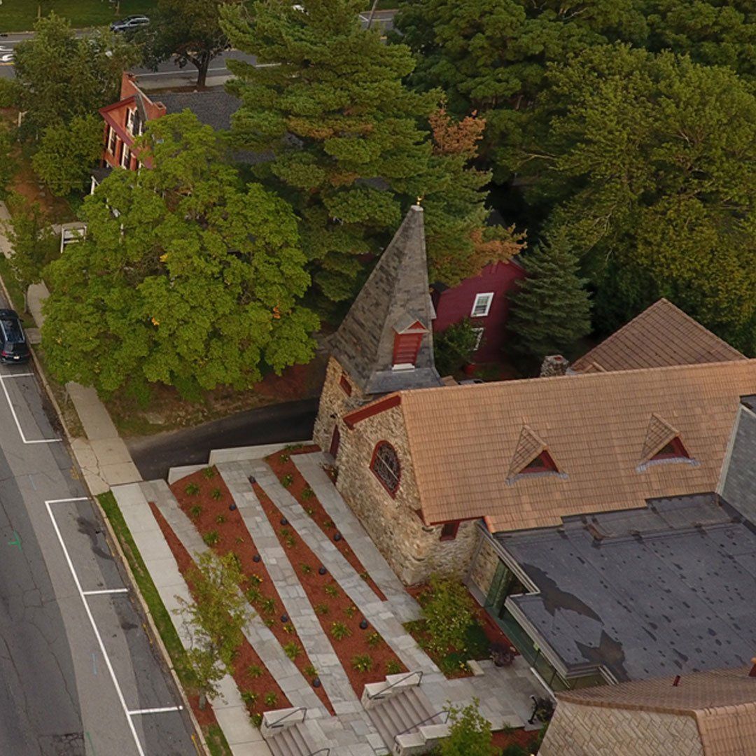 An aerial view of a church surrounded by trees and a street.