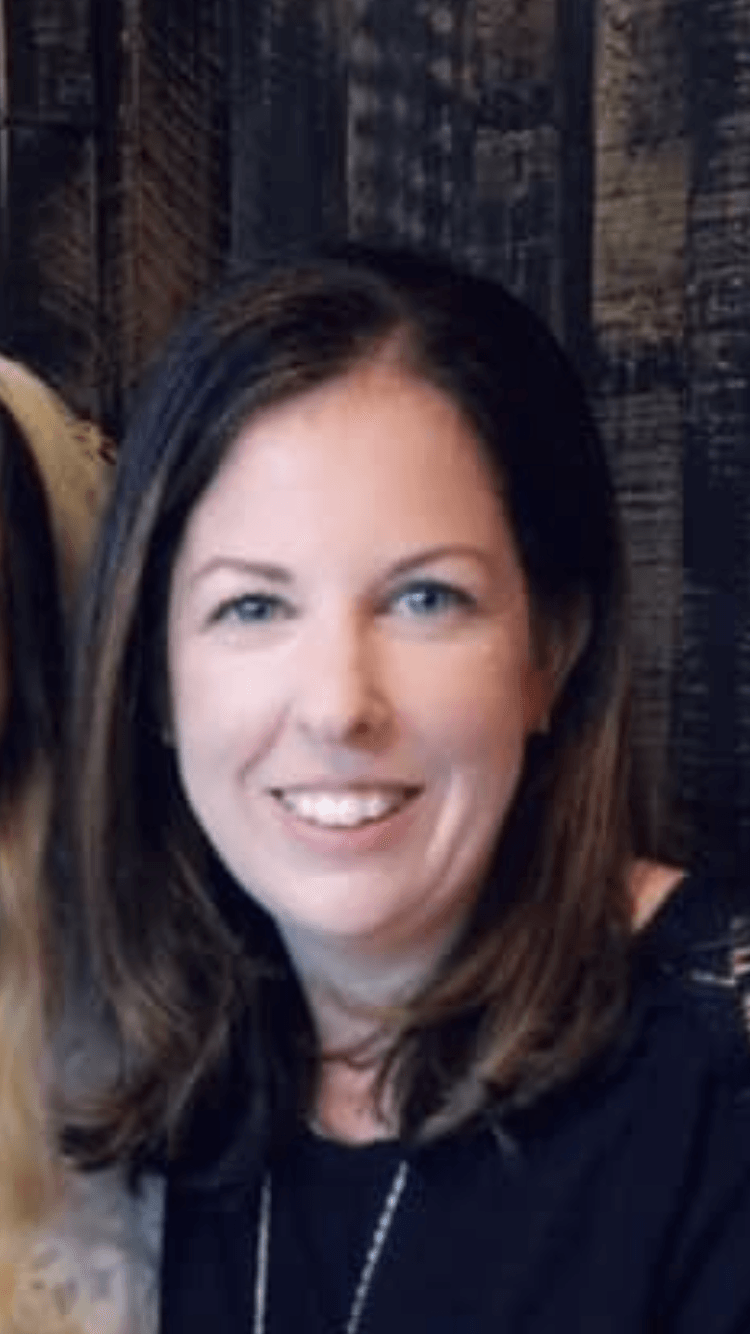 A woman in a black shirt is smiling for the camera.