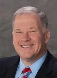 A man in a suit and tie is smiling for the camera.
