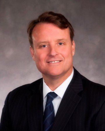 A man in a suit and tie is smiling for the camera