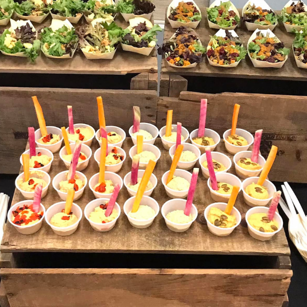 A wooden tray filled with small cups of food and spoons