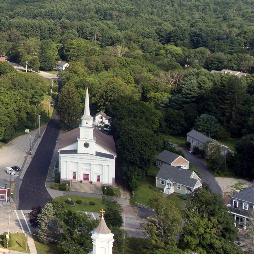 An aerial view of a church surrounded by trees and houses