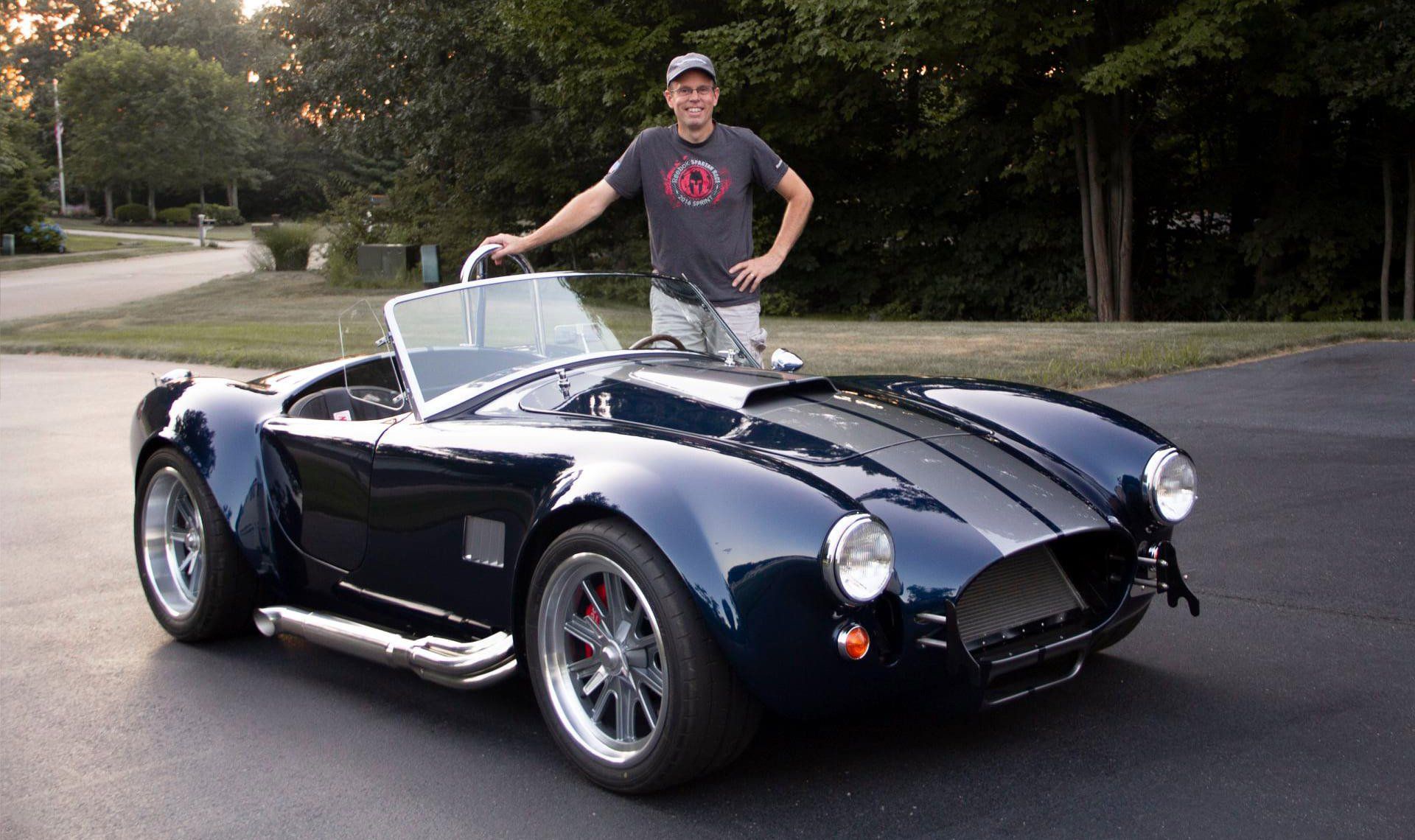 A man is standing next to a blue sports car