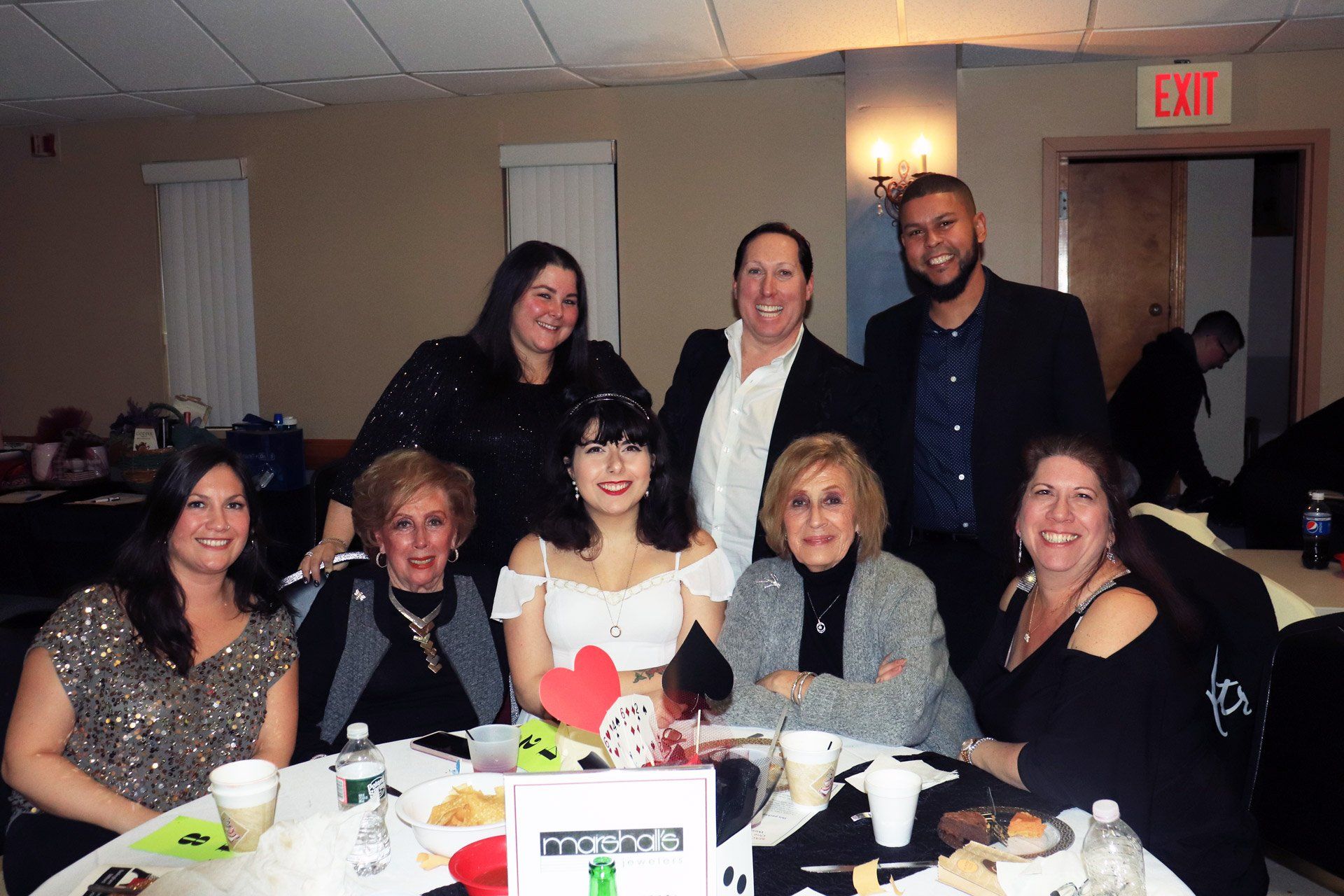 A group of people sitting around a table with an exit sign in the background