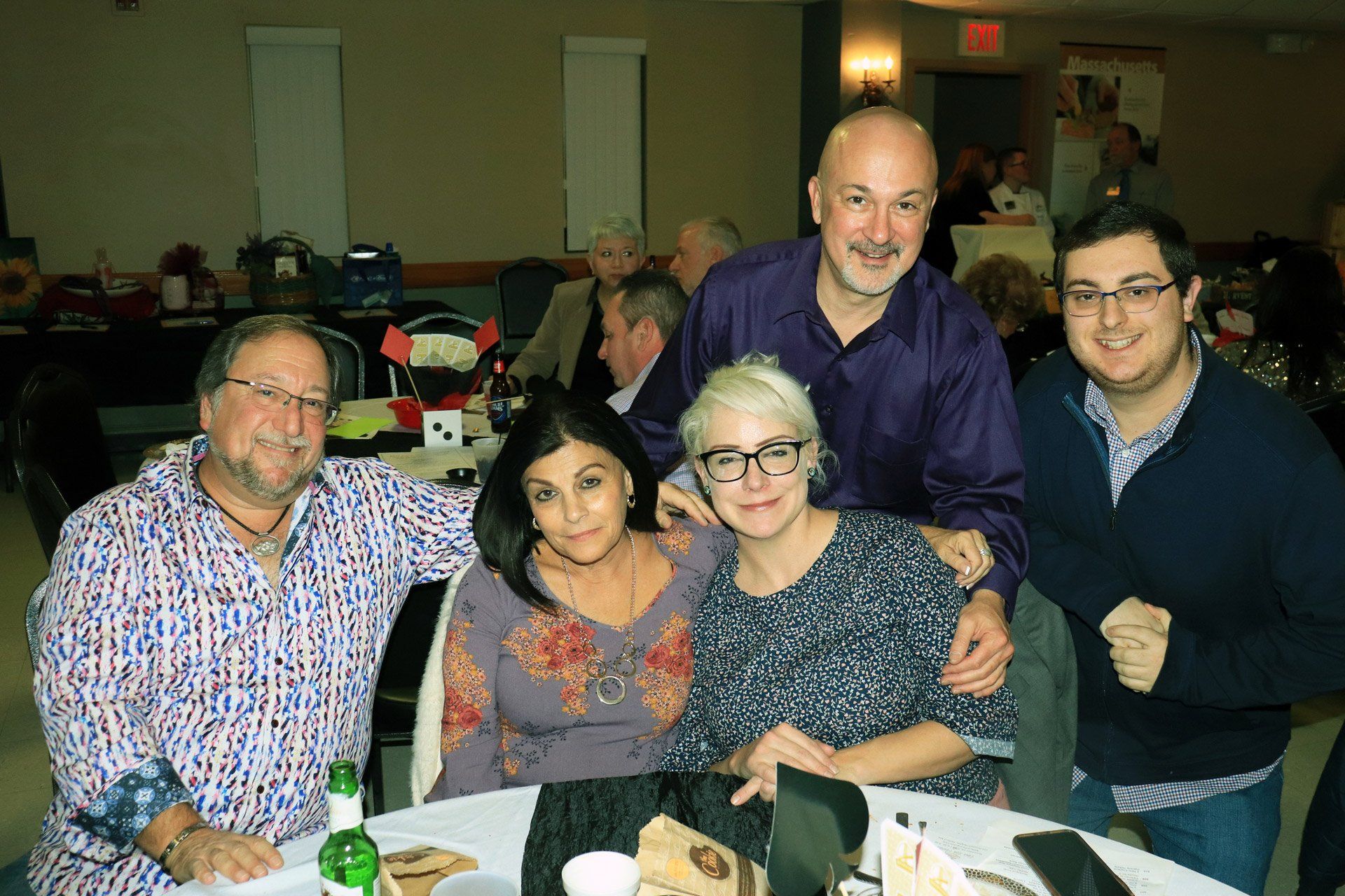 A group of people are posing for a picture while sitting at a table.