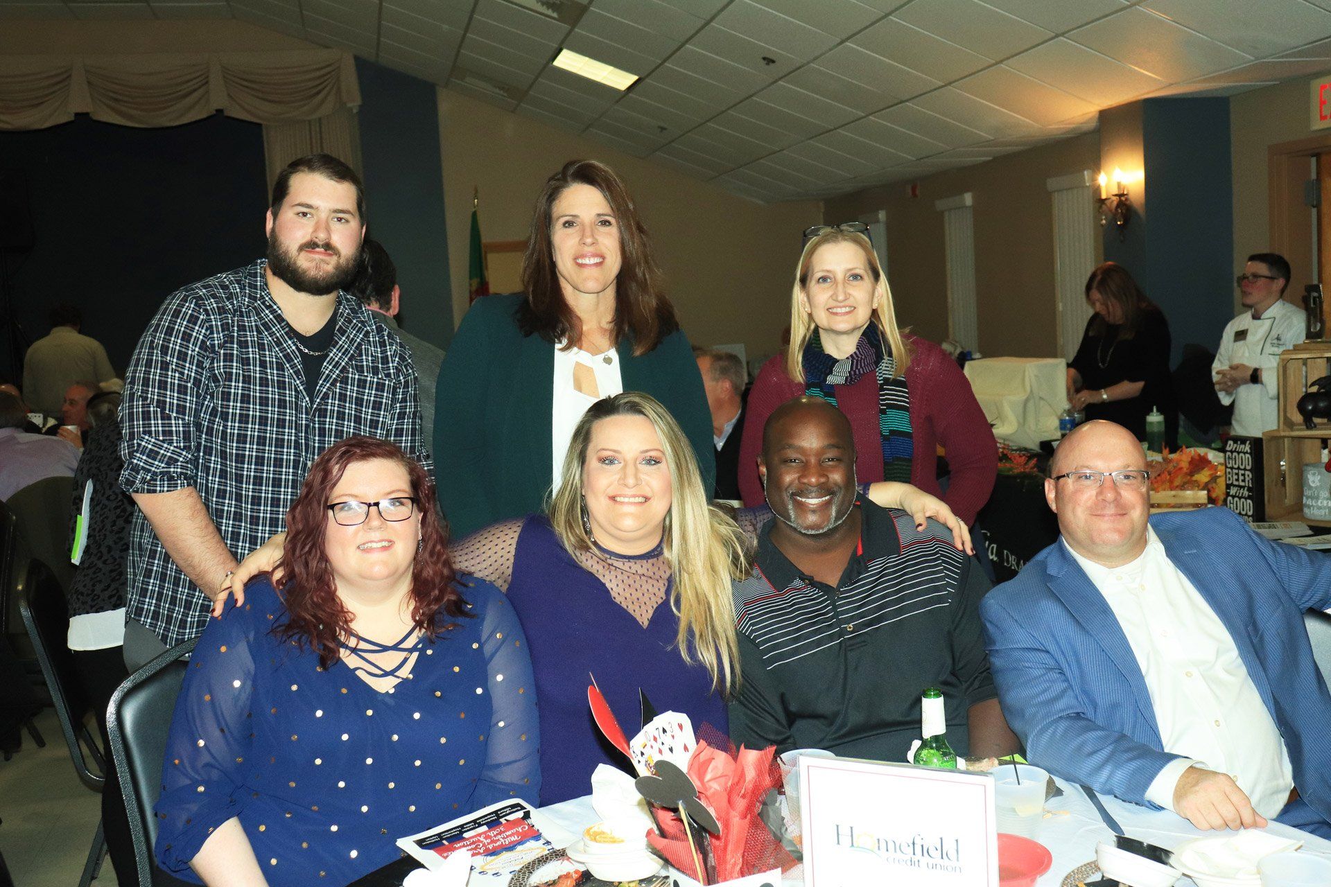 A group of people are posing for a picture while sitting at a table.