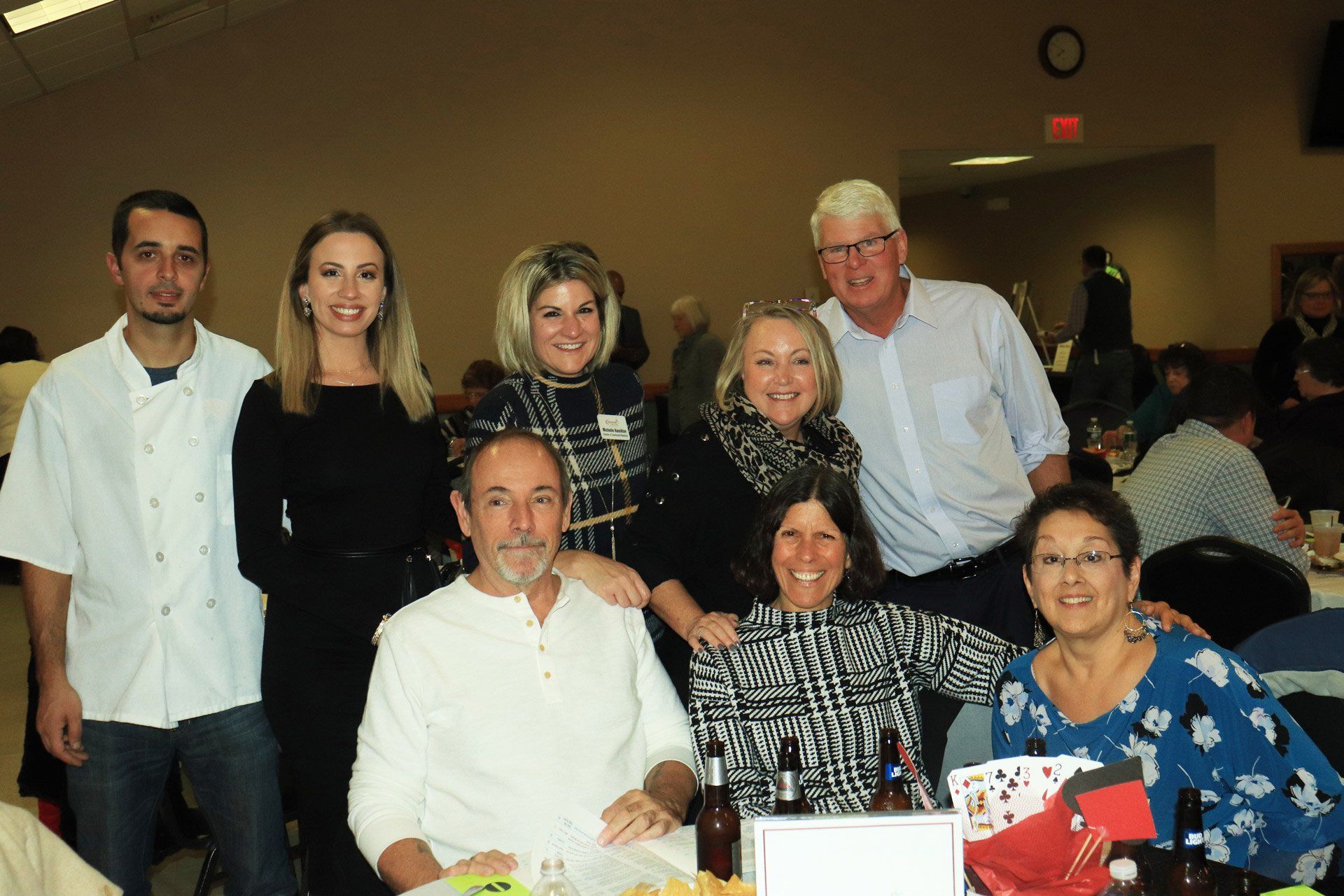 A group of people are posing for a picture while sitting at a table.