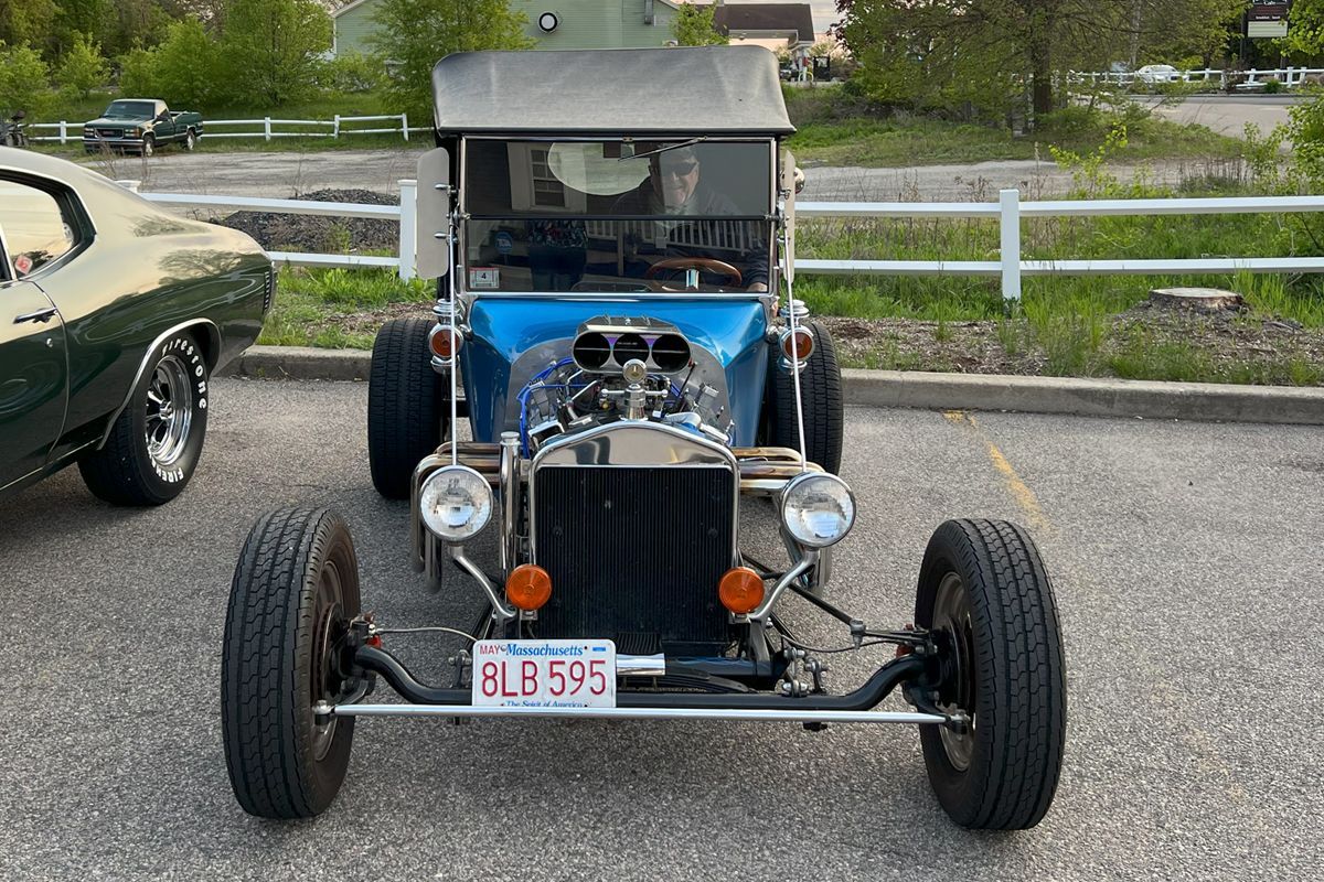 A blue car is parked in a parking lot next to a green car.