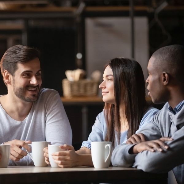 A group of people are sitting at a table drinking coffee.