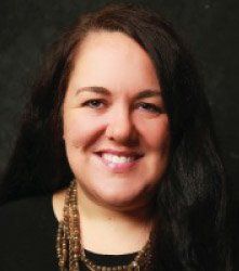 A woman is smiling for the camera and wearing a necklace.