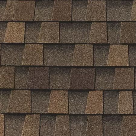A close-up view of overlapping architectural asphalt roof shingles in varying shades of brown and tan.