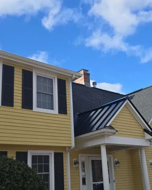 A yellow house with black shutters and a black roof