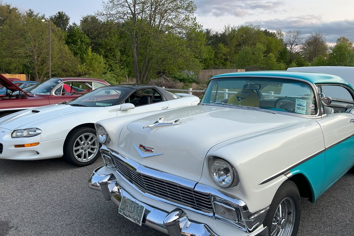 A white and blue car is parked next to a white car in a parking lot.