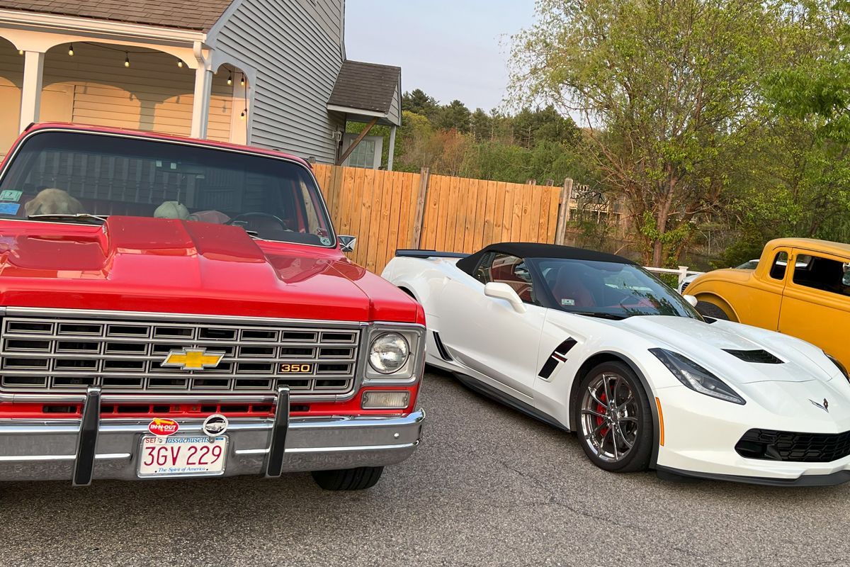 A red truck and a white sports car are parked next to each other.
