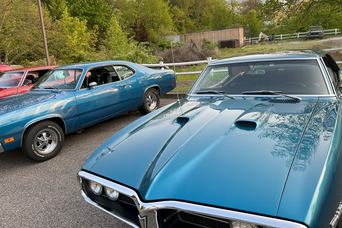 Two blue cars are parked next to each other in a parking lot.