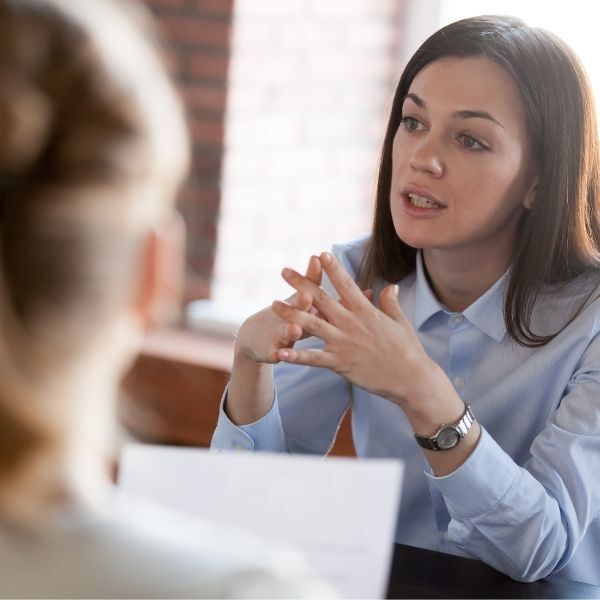 A woman is sitting at a table talking to another woman.