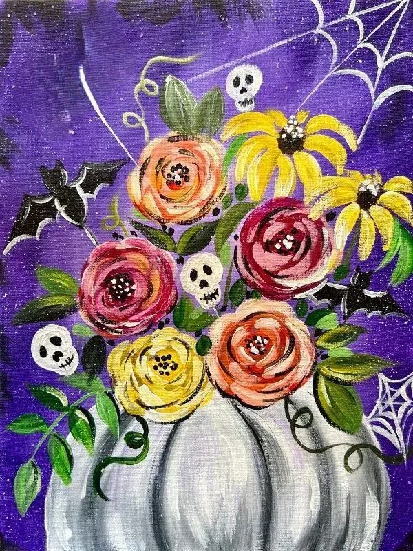 Halloween floral arrangement in a white pumpkin, with bats, skulls, and a spiderweb on purple background.