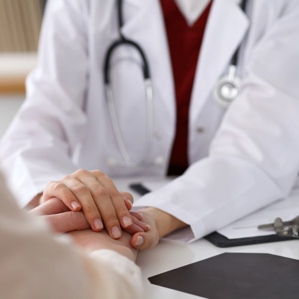 A doctor is holding the hand of a patient