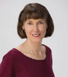 A woman in a red sweater is smiling for the camera.