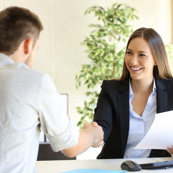 A woman is shaking a man 's hand while holding a piece of paper