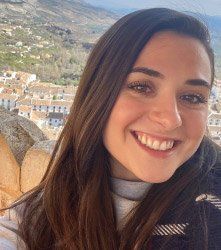 A close up of a woman 's face smiling with a mountain in the background.
