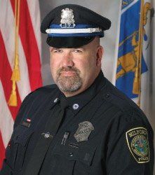 A man in a police uniform is standing in front of a flag.