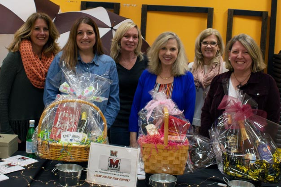 A group of women standing around a table with baskets on it.