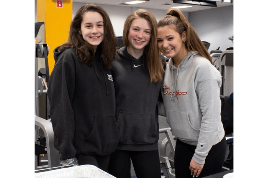 Three young women are posing for a picture in a gym.