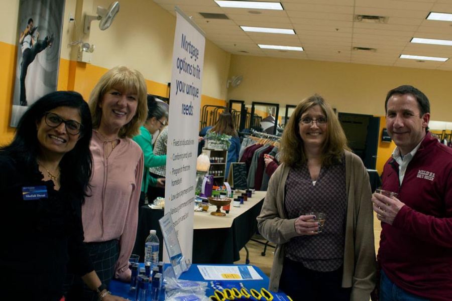 A group of people standing around a table in a room with a sign that says ' hiring volunteers ' on it