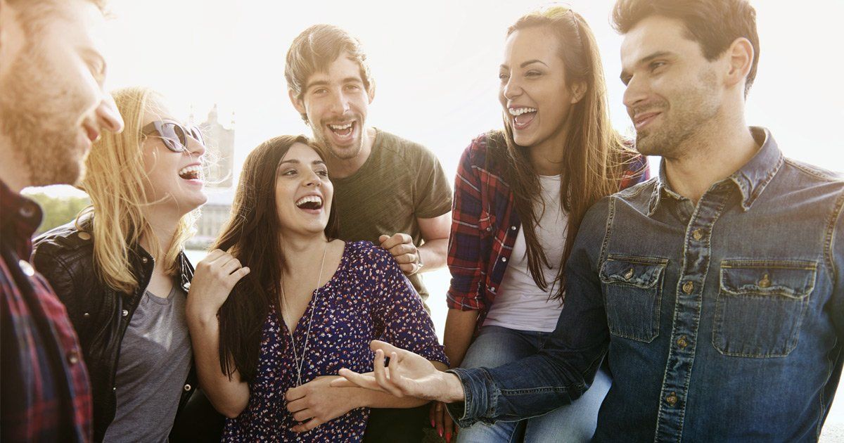 A group of young people are sitting next to each other and laughing.