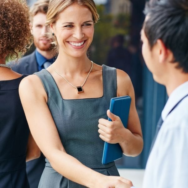 A woman in a grey dress is shaking hands with a man