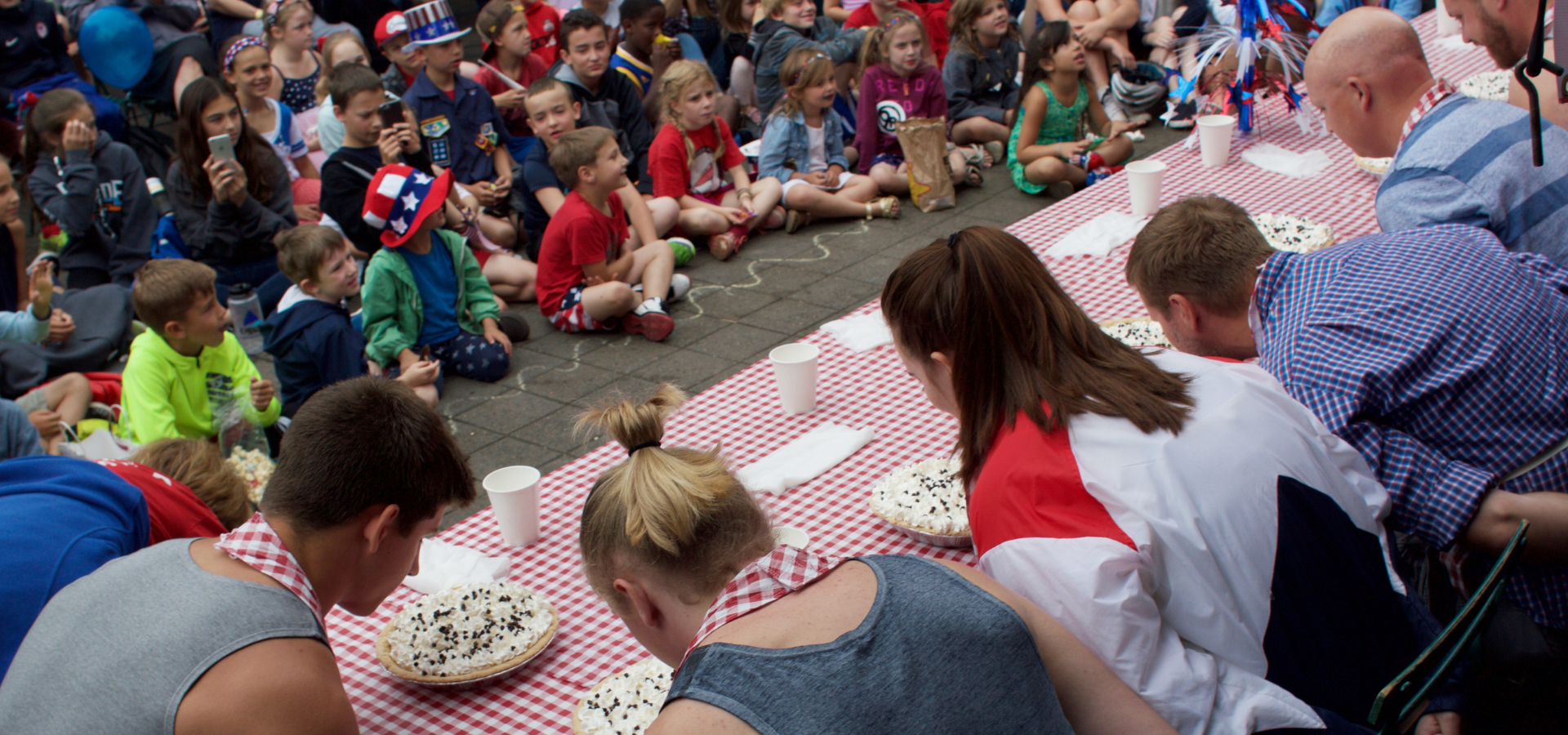 A large group of people are sitting around a table eating pizza.