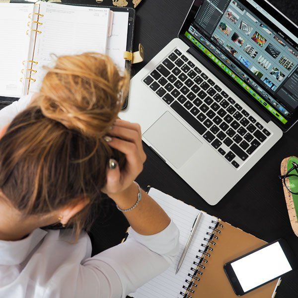 A woman is sitting at a desk with a laptop and a cell phone