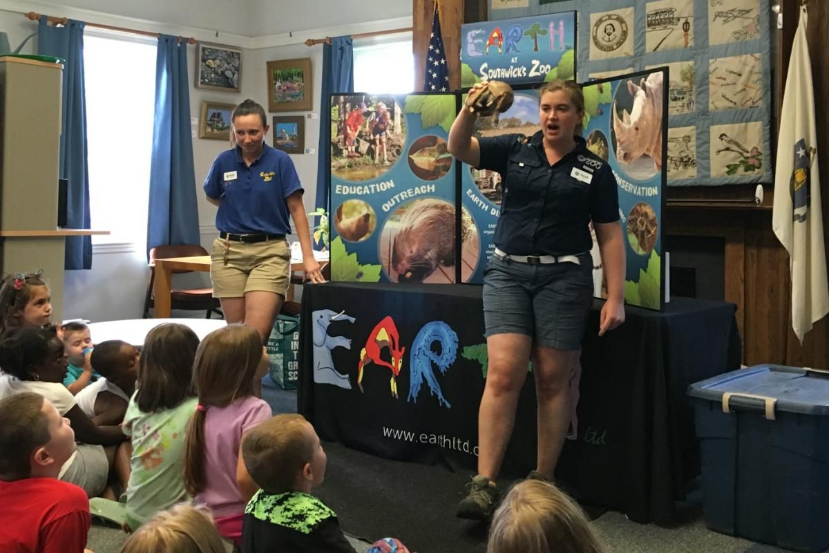 A group of children are sitting in front of a sign that says earth