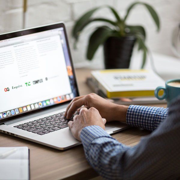 A person is typing on a laptop that says google on the screen