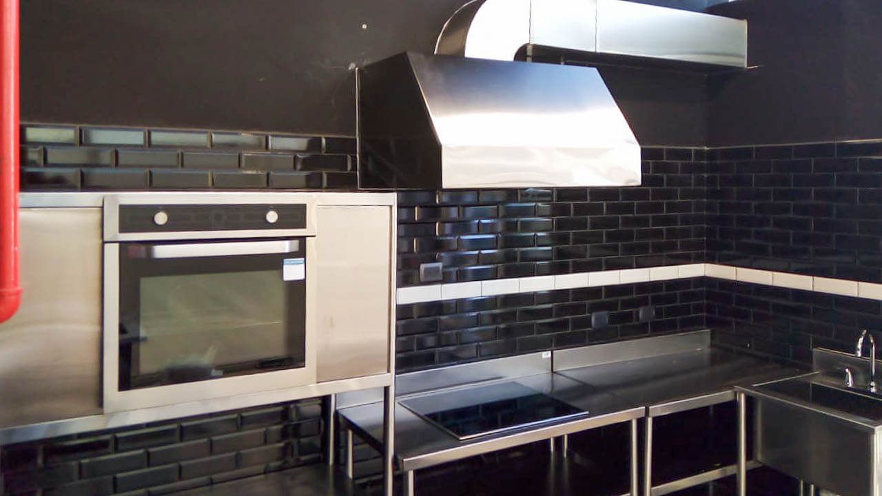 Una cocina con azulejos negros y electrodomésticos de acero inoxidable