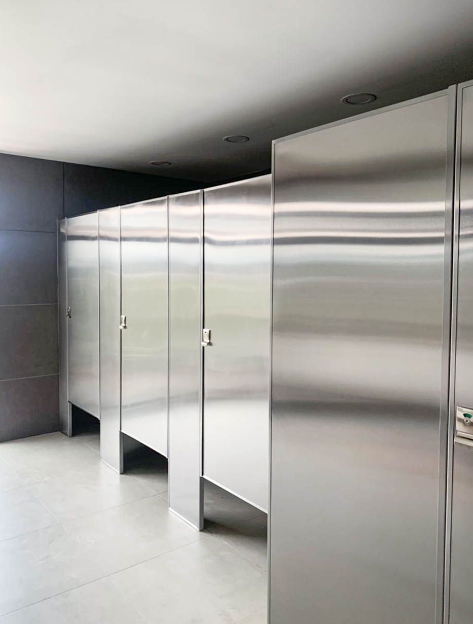 Una fila de cubículos sanitarios de acero inoxidable en un baño público.