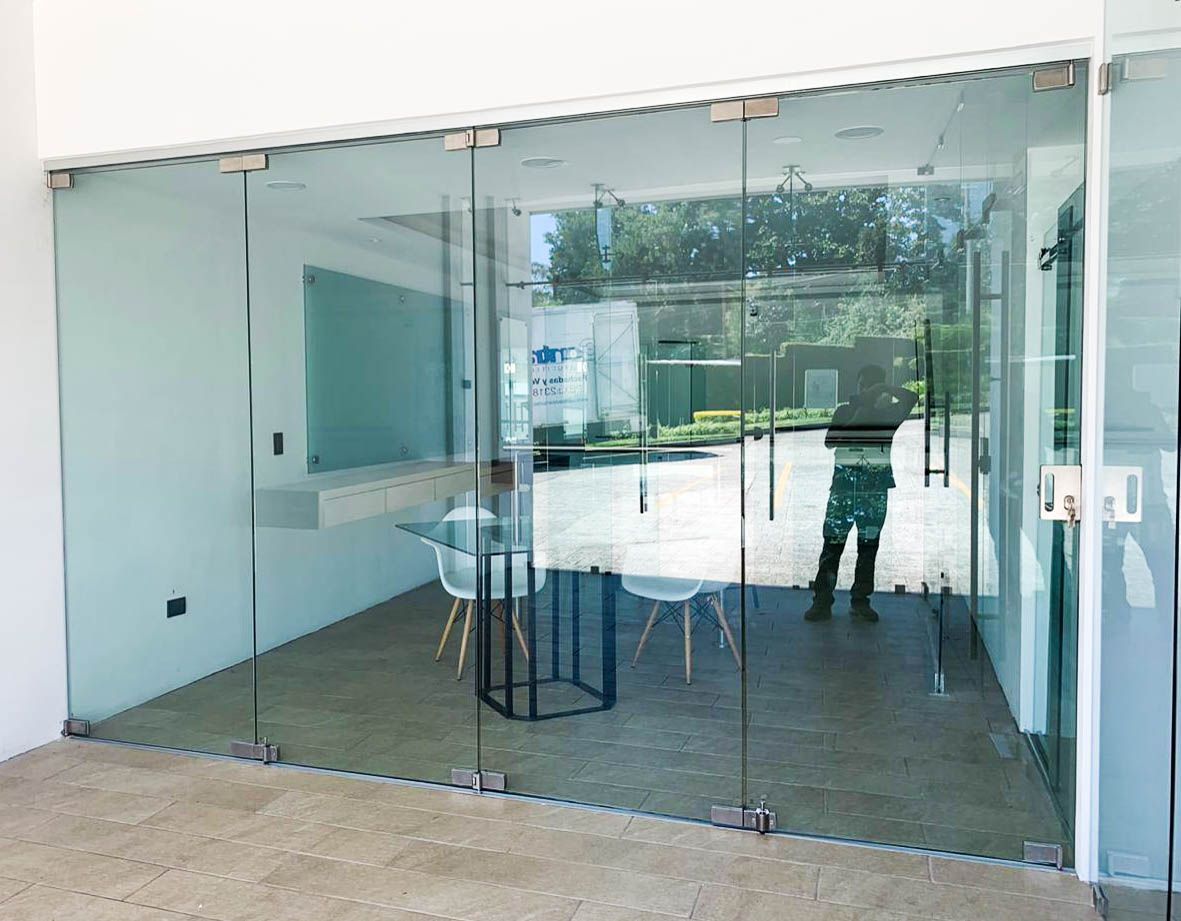 Una habitación con una mesa y sillas detrás de una pared de cristal.