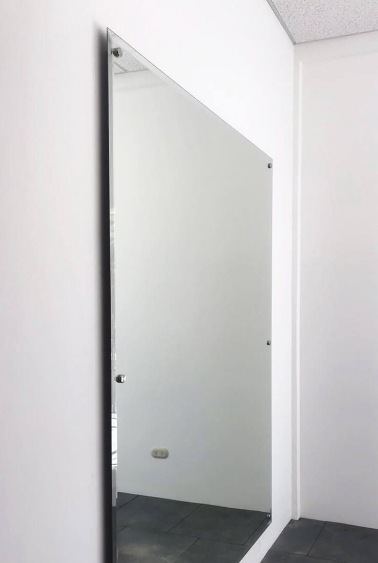 Un gran espejo cuelga de una pared blanca de una habitación.