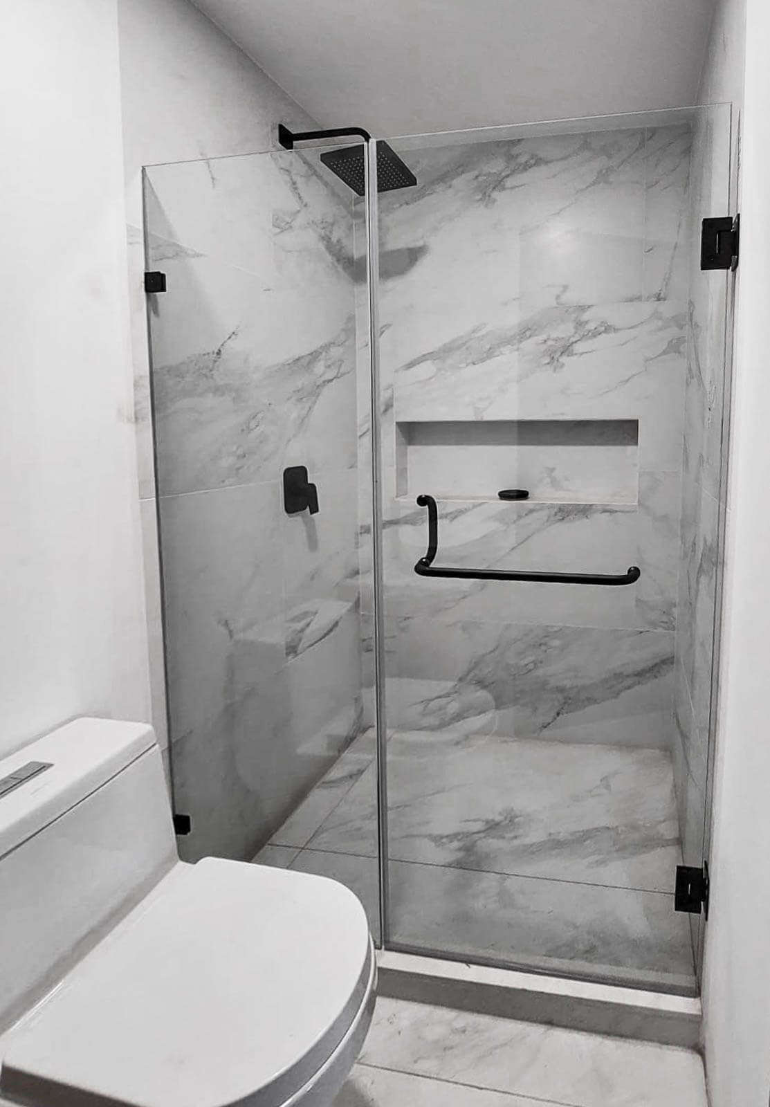 Una fotografía en blanco y negro de un baño con inodoro y ducha.