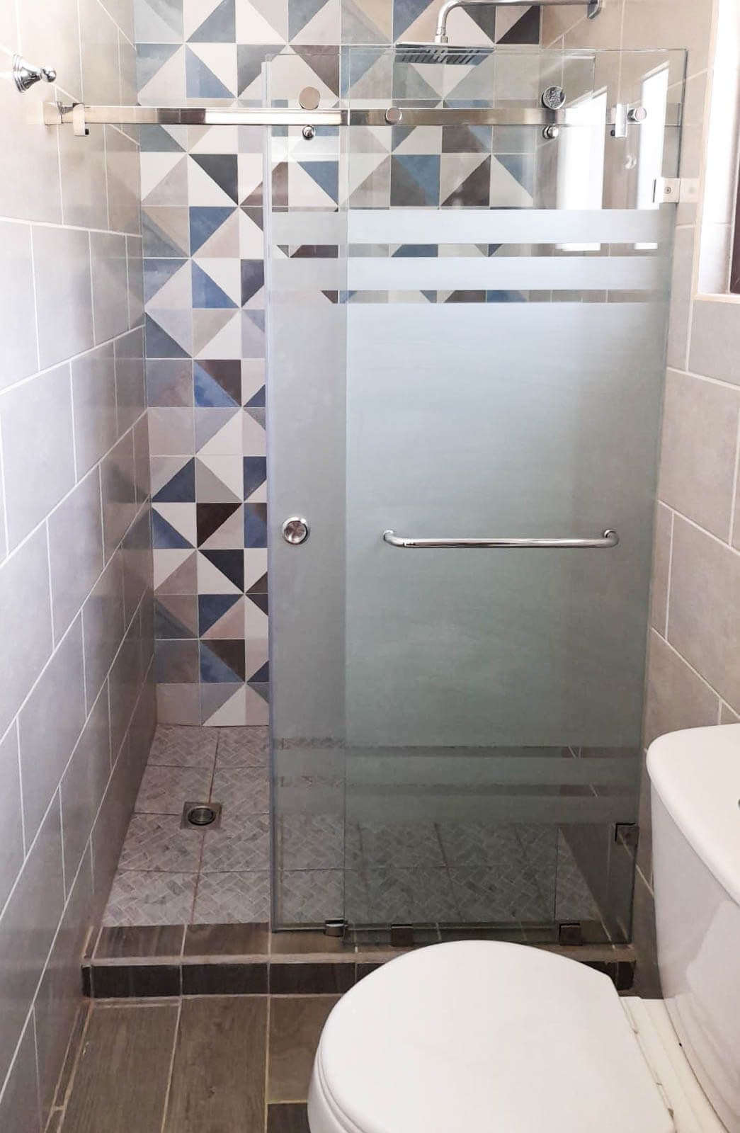 Un baño con inodoro y cabina de ducha con puerta corredera de cristal.