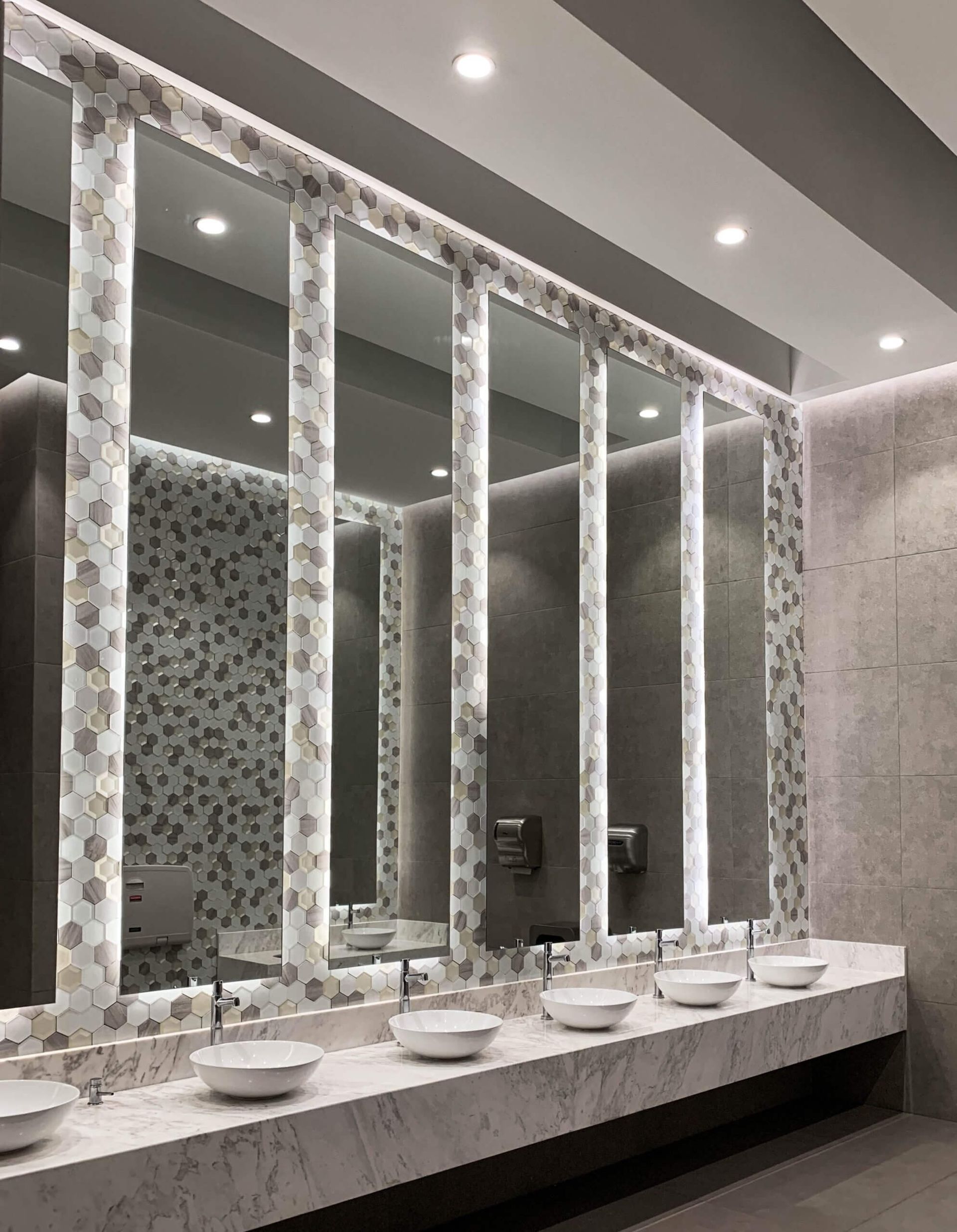 Un baño con muchos lavabos y espejos