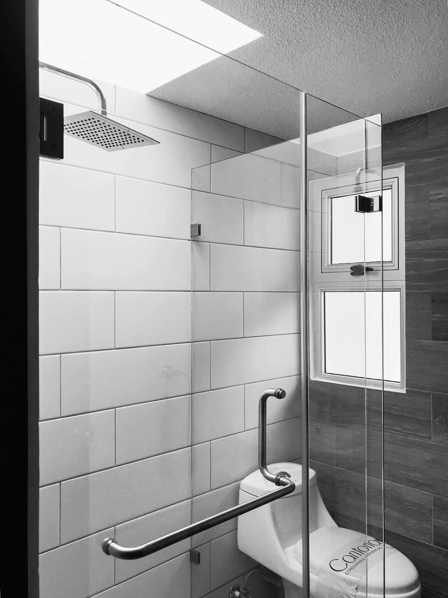 Una fotografía en blanco y negro de un baño con inodoro y ducha