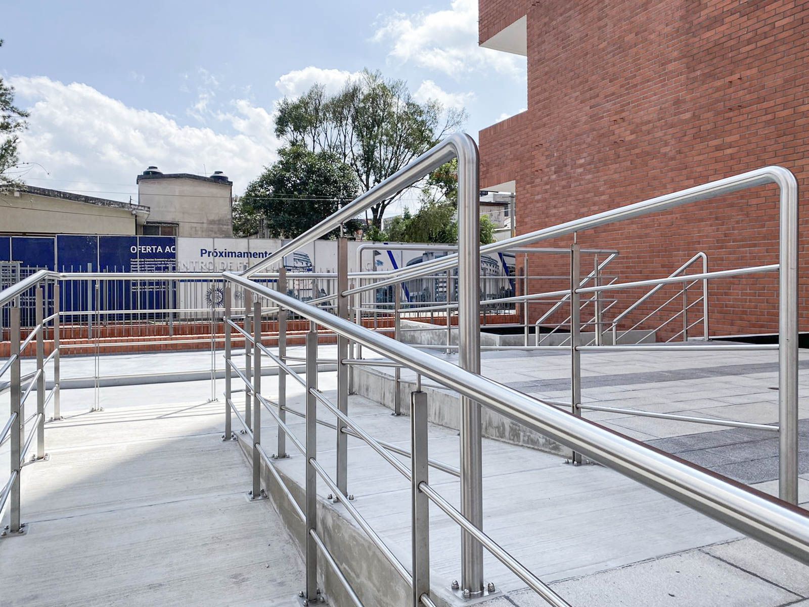 Una escalera con barandilla de acero inoxidable y un edificio de ladrillo al fondo