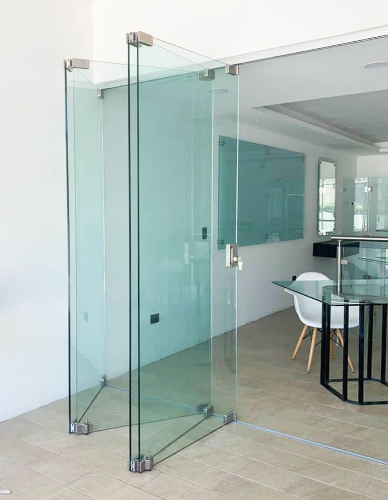 Una habitación con mesa y sillas y una puerta de cristal.