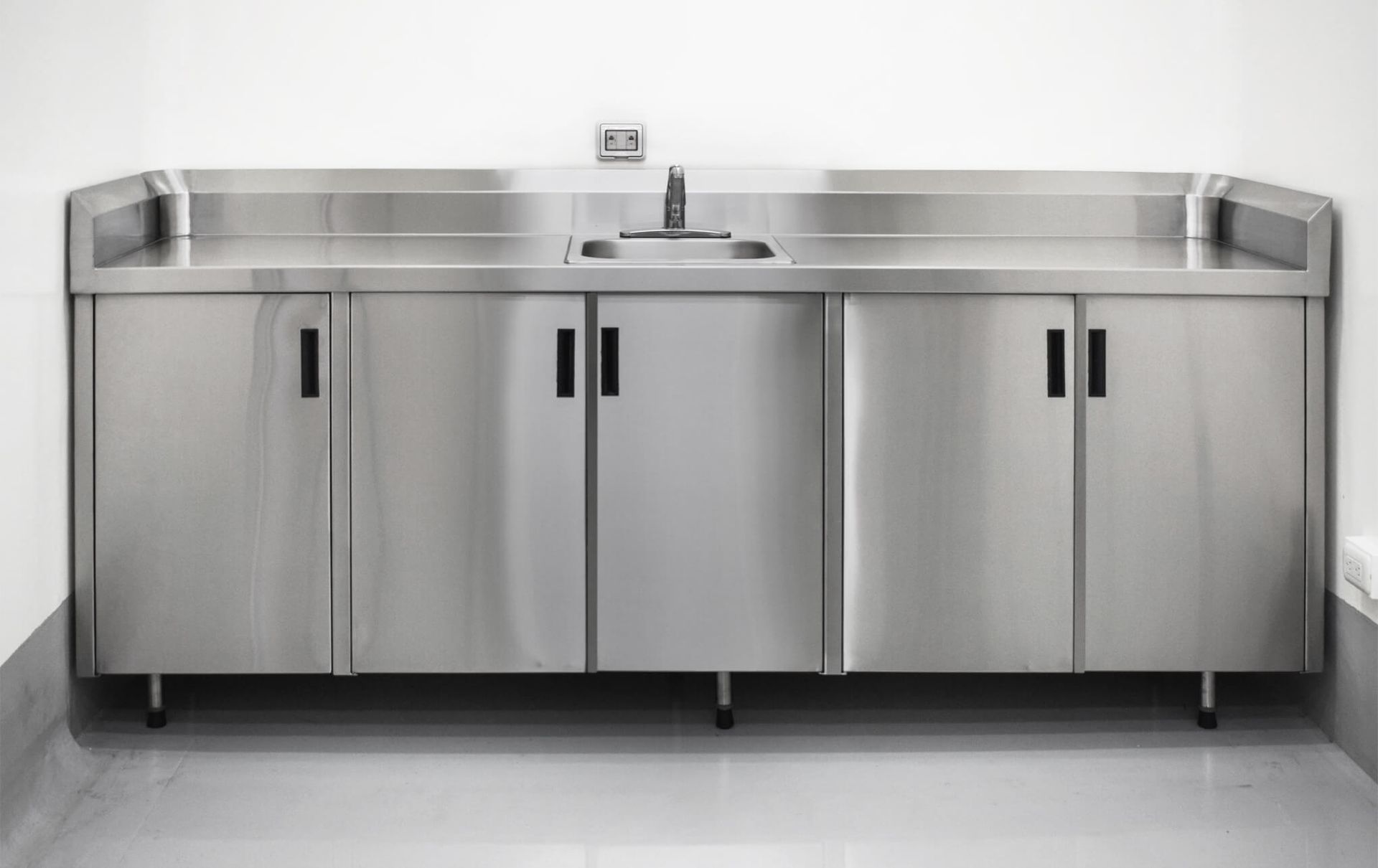 Una encimera de cocina de acero inoxidable con fregadero y gabinetes