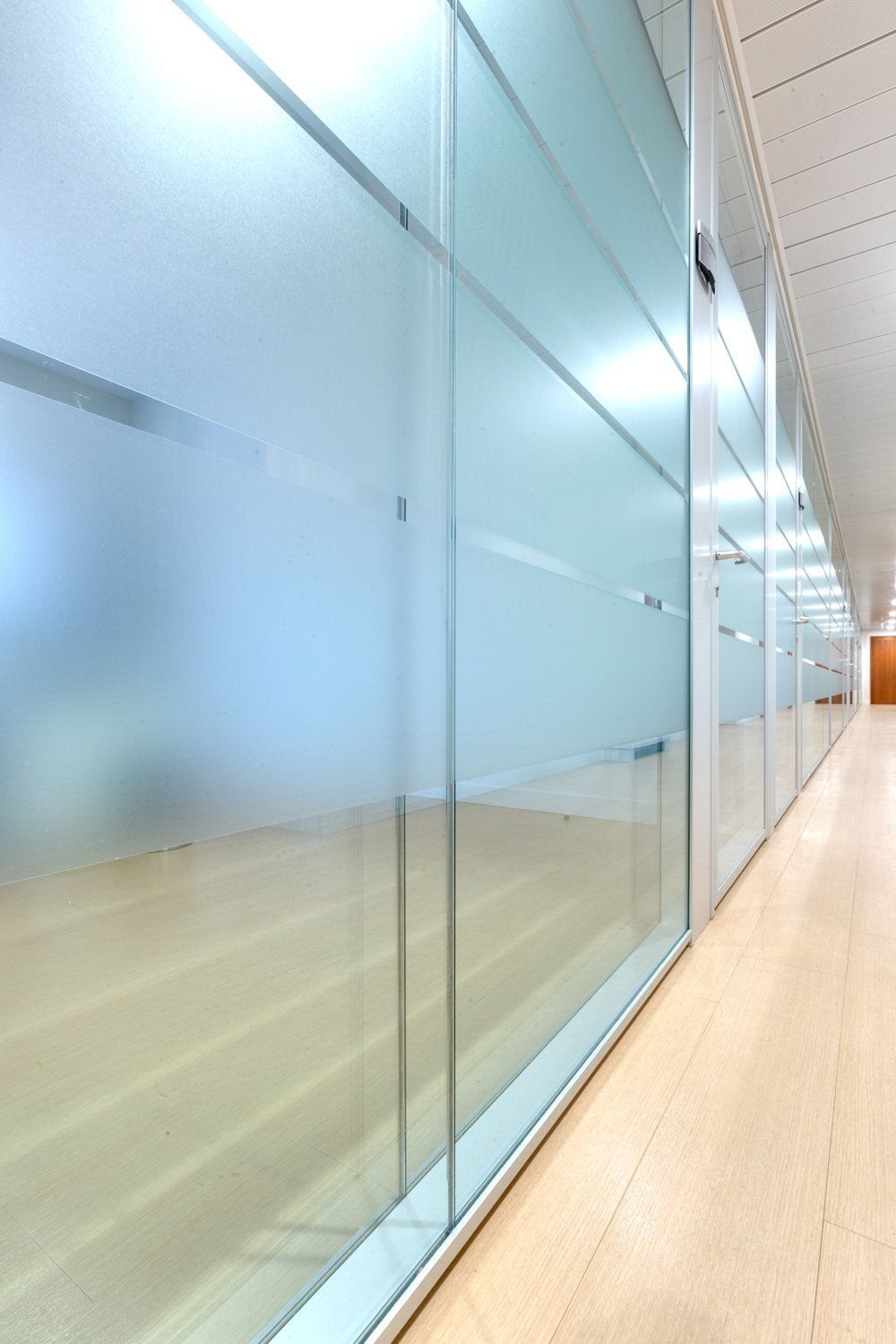 Un largo pasillo con paredes de cristal y suelo de madera.