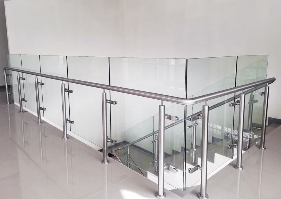 Una escalera con barandilla de cristal y barandilla de acero inoxidable.