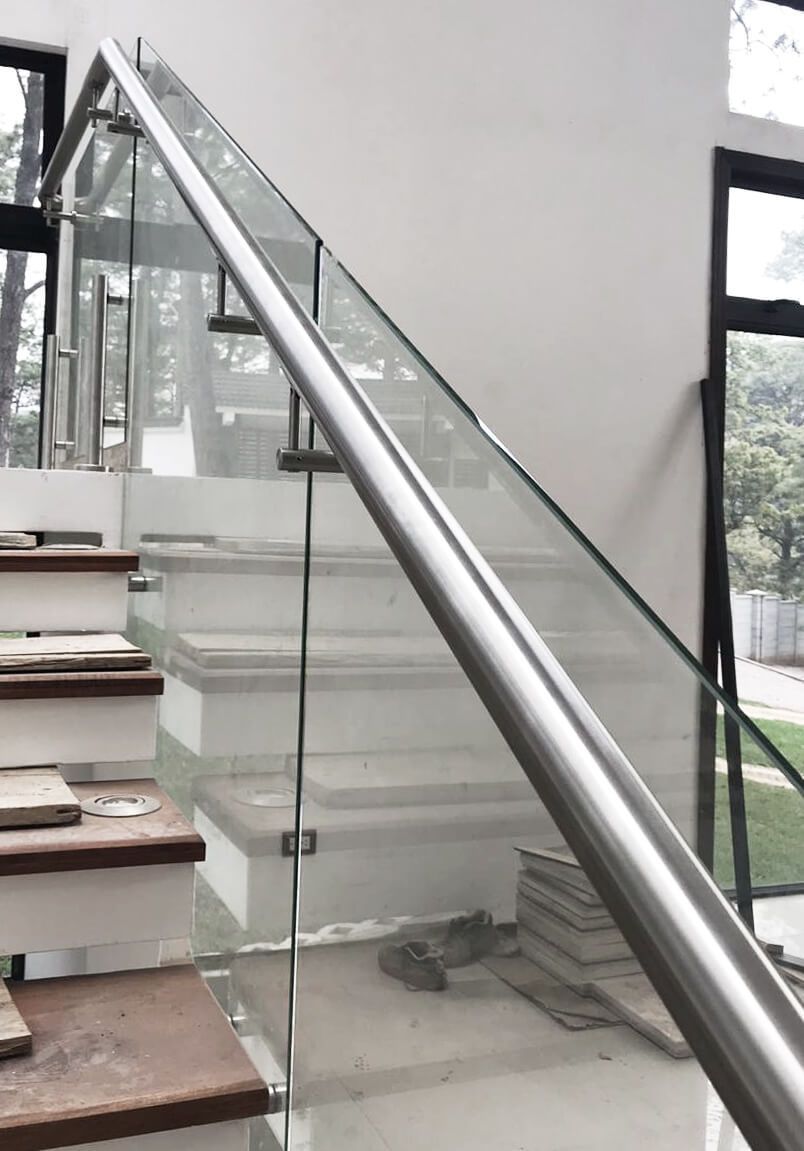 Una escalera con barandilla de cristal y barandilla de acero inoxidable