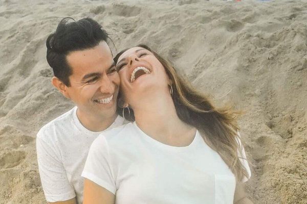 A man and a woman are laughing on the beach. Maternity